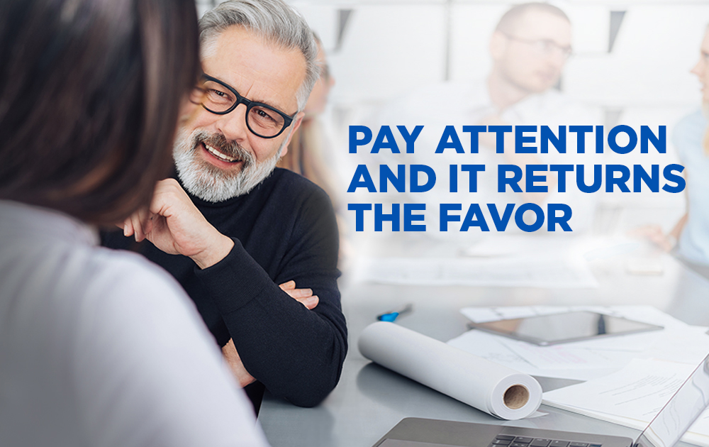 Senior businessman listening carefully to a female colleague in the office in an over the shoulder view of his face