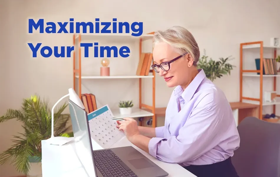 "Professional woman with short gray hair sitting at a desk, reviewing a calendar while working on a laptop, with the text 'Maximizing Your Time' displayed beside her."